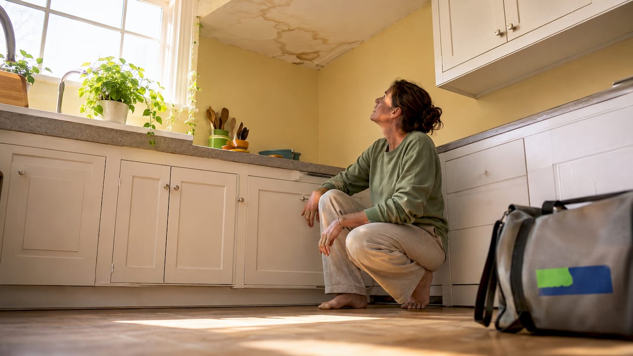 Woman inspecting ceiling water stain at home